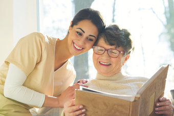 caregiver and a senior woman reading a book